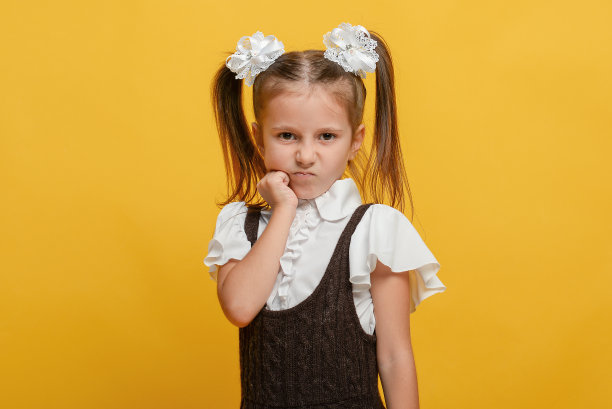 黄色背景下穿着制服的滑稽小女生。情感上的肖像。回到学校图片下载