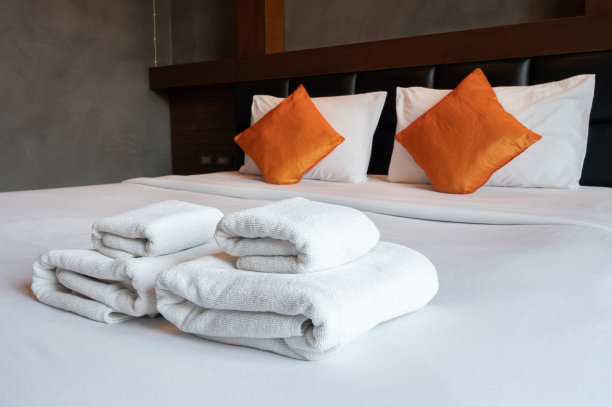 靠近舒适的床和毛巾在酒店卧室装饰舒适的风格。图片下载