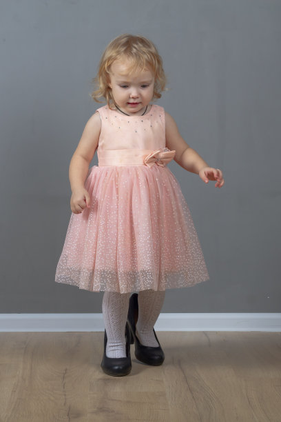 可爱的小女孩2岁的白人走在黑色妈妈的大高跟鞋在粉红色的舞会礼服图片下载