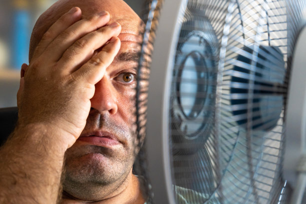 一个中年白人男子在一个非常炎热的日子里拿着风扇凉快图片下载