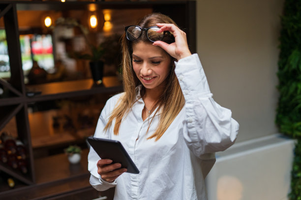 在办公室或咖啡厅站着拿着平板电脑的成年白人女性企业家的正面照片图片下载