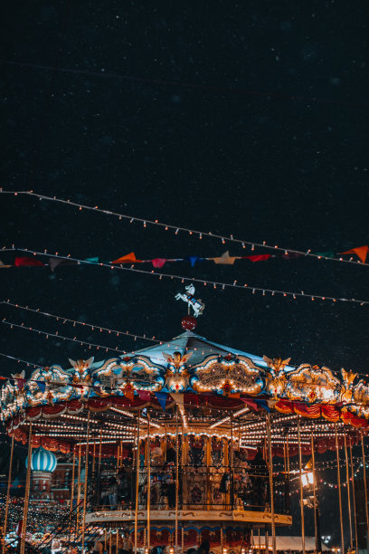 节日儿童的旋转木马在新年的气氛中欢腾飞舞着雪花。图片下载