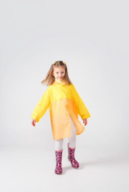 一个穿着黄色雨衣和靴子的小女孩的肖像。在白色背景上隔离。图片下载