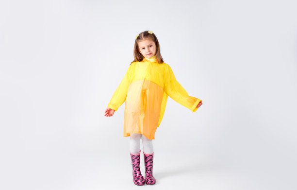 一个穿着黄色雨衣和靴子的小女孩的肖像。在白色背景上隔离。图片下载