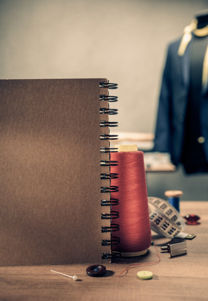 桌上摆放笔记本及缝纫工具。服装工作室工作场所的概念图片下载