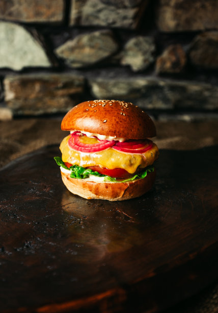 美国汉堡与恰克卷肉，切达奶酪和其他成分照明照片在黑暗的背景。图片下载