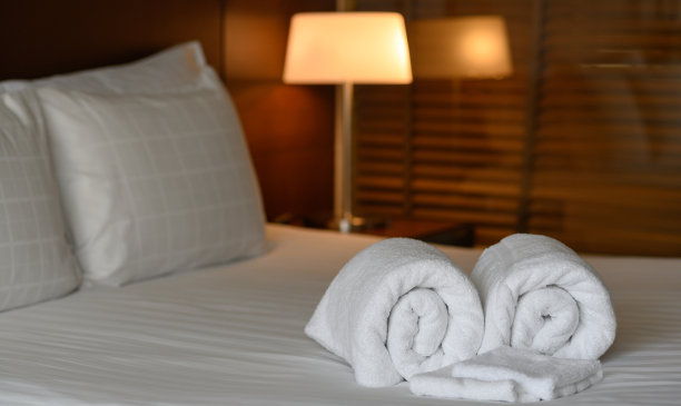 干净的白色毛巾设置在床上的酒店卧室，放松，度假，度假的概念。图片下载