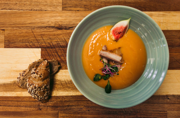 鳕鱼片配甘薯和其他美味配料制成的橙汤。食物的顶部视图与新鲜法棍在木制背景-照片从上面。图片下载