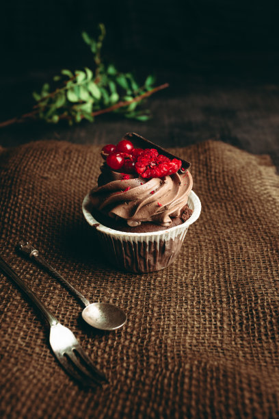 美丽可口的纸杯蛋糕在黑暗和乡村的背景。奶油芝士草莓小蛋糕。巧克力和焦糖的纸杯蛋糕。图片下载