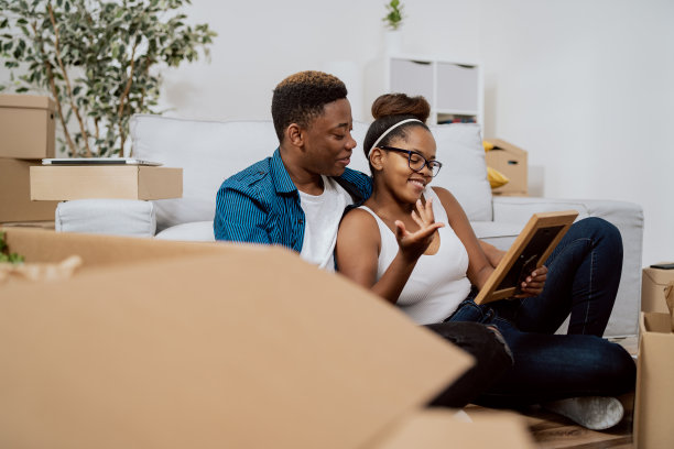 一对相爱的夫妇搬进了他们自己的第一间公寓，他们坐在地板上打开装有物品的箱子，女人给男人看了一张相框里的老照片，男孩拥抱着他心爱的回忆图片下载