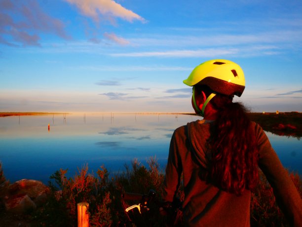 女孩骑自行车从后面看日落图片下载