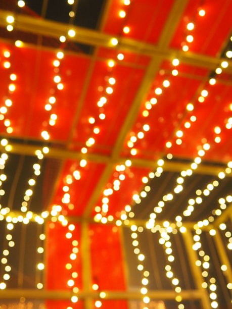 圣诞夜的散景。美丽的圆形散景亮点。在黑暗中有红色、黄色、金色、白色。新年的喜庆背景圣诞快乐。散焦模糊。城市街道装饰图片下载