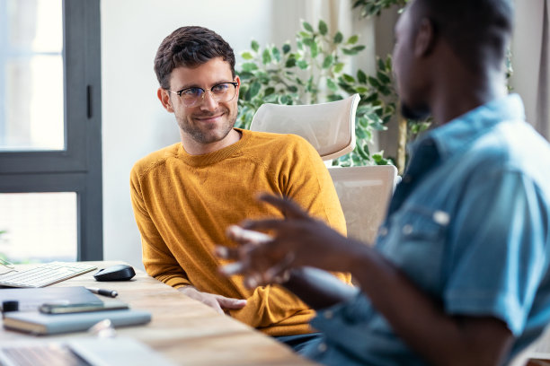 两位平面设计师在现代创业办公室里休息，聊天，玩得很开心。图片下载