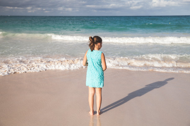 一个穿蓝裙子的小女孩站在沙滩上，后视镜图片下载