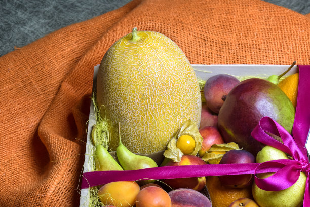 多汁的成熟水果和浆果漂亮地堆放在木箱里，用粉红色的丝带绑着。黑暗的背景。送餐，礼品水果套装。健康饮食观，饮食观。副本的空间。有选择性的重点。图片下载