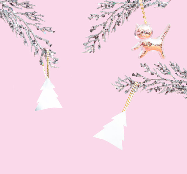 银色的树枝和粉红色背景上的圣诞树。黄金装饰的猫。圣诞快乐的概念图片下载