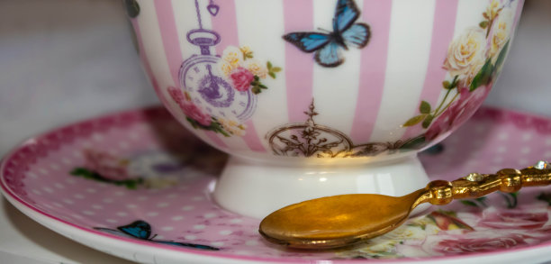 一个金色的勺子在一个彩色的茶杯茶碟上的特写图片下载