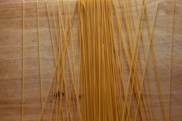 意大利面在木板上。意大利面食。黄色的意大利面撒在桌子上。食品的背景下,意大利。意大利艺术背景。高质量的照片图片下载