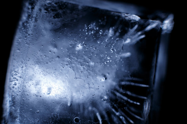 水晶冰块反射黑色的背景。在黑暗的背景下，近距离观察自然冰块。宏。图片下载