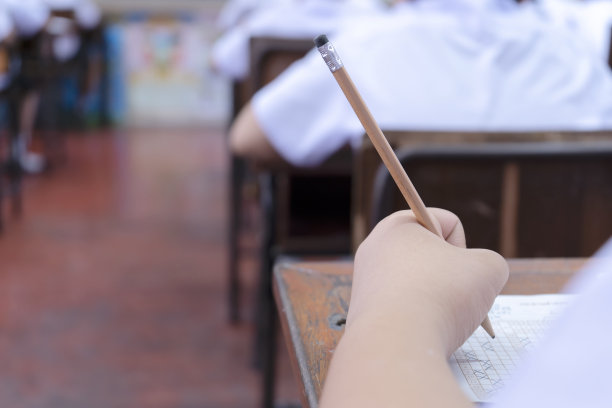 试卷放在桌子上，手拿着铅笔。图片下载