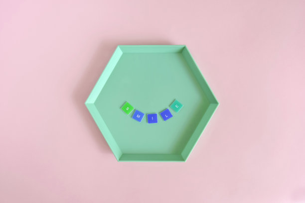 微笑-字由彩色字母在绿色六角形板上粉红色的背景。前视图。副本的空间。有选择性的重点。图片下载