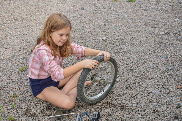 这个小女孩弄坏了一个自行车轮子，正在做没有处理的修补照片图片下载