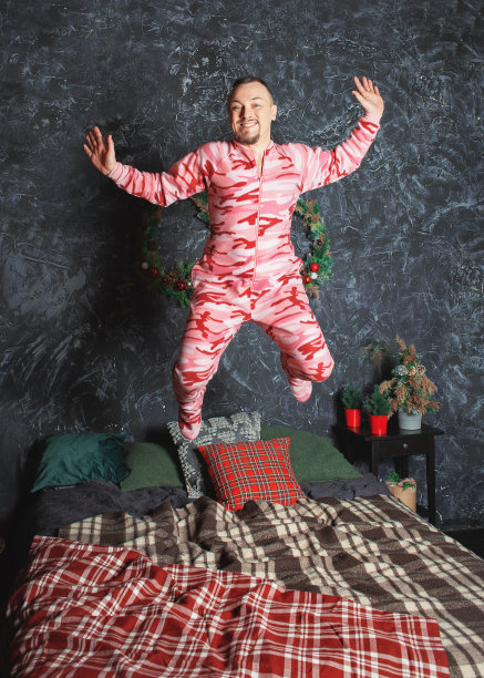 快乐的滑稽快乐的男人在粉红色的睡衣跳床图片下载