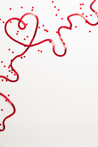 心形的红色丝带在白色的背景与五彩纸屑。情人节快乐的概念。图片下载