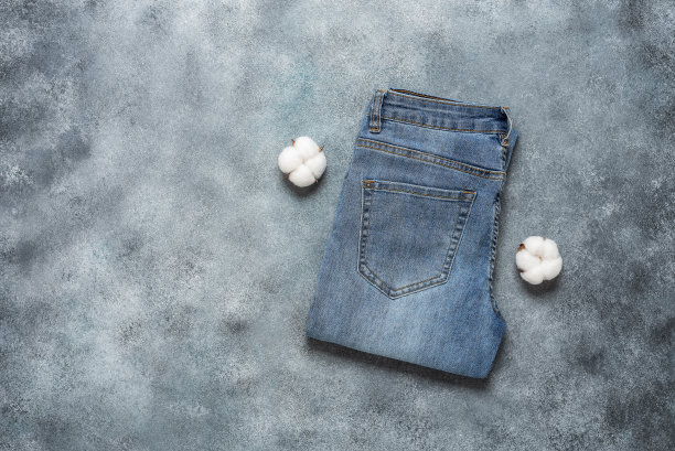 蓝色牛仔裤在灰色grunge背景。俯视图，平铺。图片下载