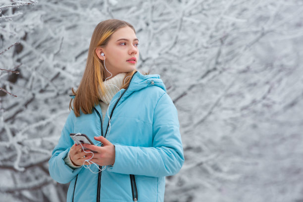 在冬季公园里用手机听音乐的少女图片下载