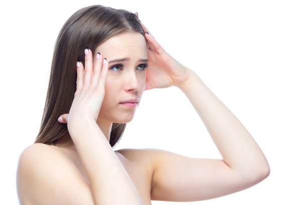 这张照片拍摄的是一个年轻漂亮的女孩，她正经历着严重的头痛发作，站在白色背景上，双手靠近头部图片下载
