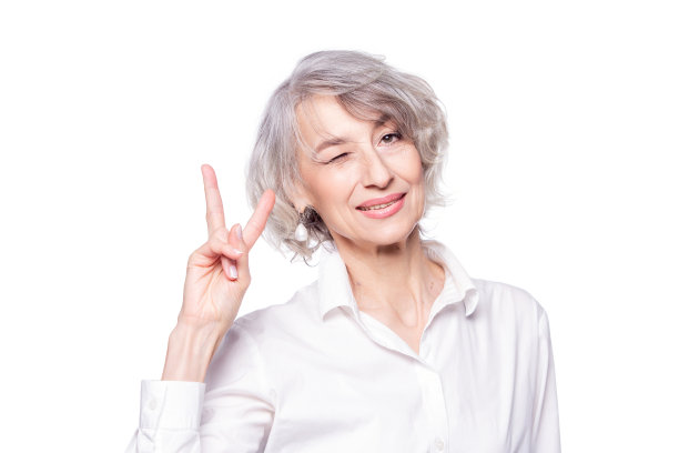近距离的肖像，资深的灰色头发的女人穿着优雅的衬衫站在孤立的白色背景微笑，快乐的脸眨眼在相机做胜利的标志图片下载