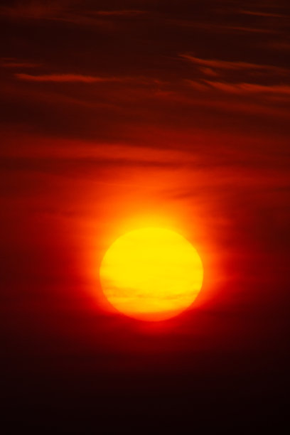 明亮温暖的太阳在天空的背景。黎明或黄昏。图片下载