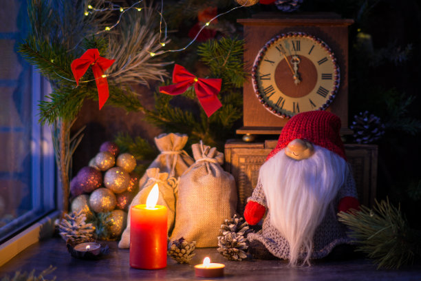 为圣诞节装饰窗户，云杉树枝上挂着红色的蝴蝶结，圣诞老人带着一袋礼物，点燃蜡烛，圣诞装饰品和冷杉球果。图片下载