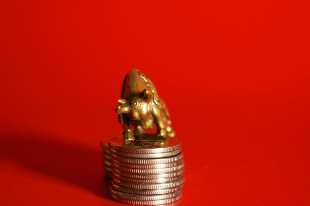 红色背景上有硬币的公牛雕像。特写镜头。图片下载