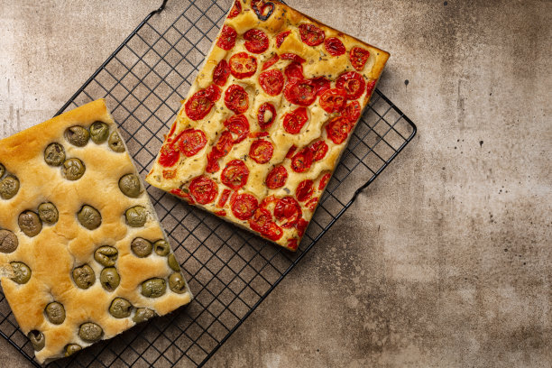 两份意大利佛卡夏面包，配上番茄、香草和橄榄。棕色的背景。俯视图，复制空间。图片下载