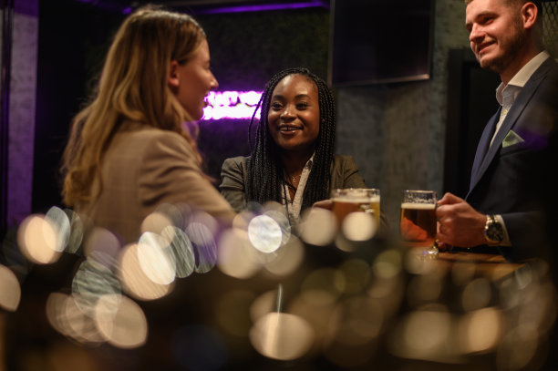 愉快的同事下班后一起在酒吧喝啤酒，用平板电脑图片下载