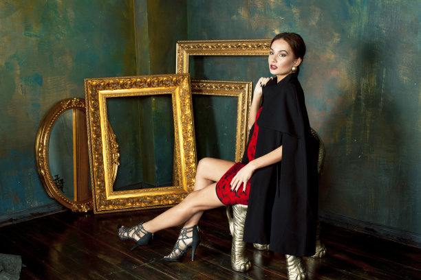 美丽富有的黑发女人在豪华的内饰附近空框，穿着时尚的衣服，生活方式的人的概念图片下载