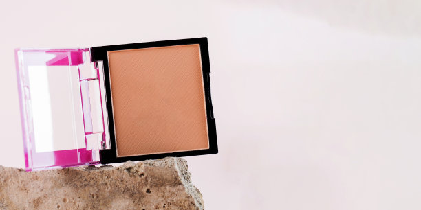 浅粉色背景的灰色石头上的粉末打开案例。本空间图片下载