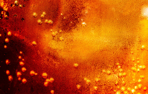 近距离观看在黑暗的可乐背景的冰块。清凉甜美的夏日饮品，泡沫和宏观气泡贴在玻璃墙上。发出嘶嘶声或浮到表面上图片下载