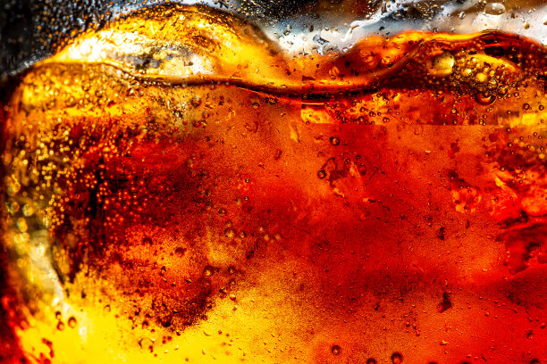 近距离观看在黑暗的可乐背景的冰块。清凉甜美的夏日饮品，泡沫和宏观气泡贴在玻璃墙上。发出嘶嘶声或浮到表面上图片下载