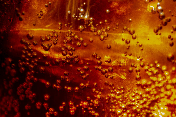 近距离观看在黑暗的可乐背景的冰块。清凉甜美的夏日饮品，泡沫和宏观气泡贴在玻璃墙上。发出嘶嘶声或浮到表面上图片下载