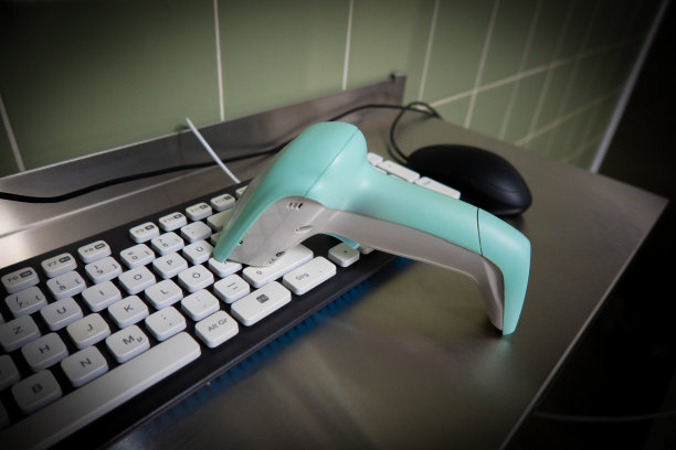 黑色的电脑键盘旁边是一个绿色的条形码扫描仪图片下载