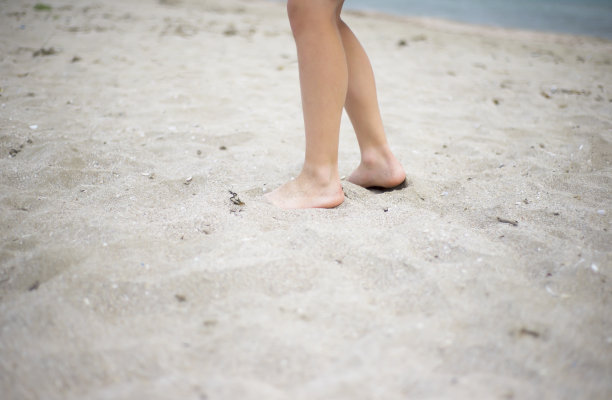赤脚少年的脚踩在沙滩上。图片下载