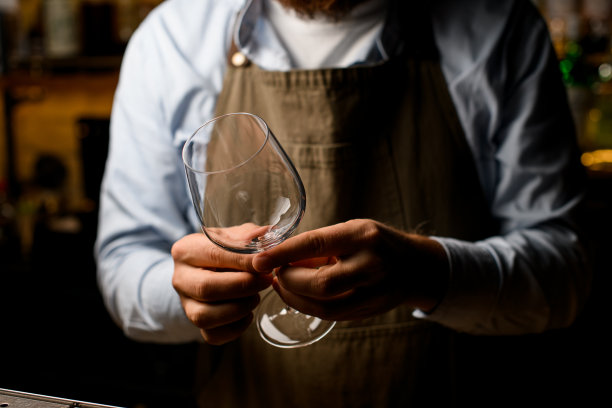 精挑细选的男调酒师双手整齐地捧着一只空的酒杯。图片下载