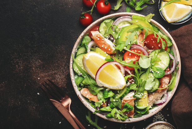 新鲜沙拉配鸡肉，番茄，芝麻，洋葱，鳄梨，芝麻和柠檬油。健康食品。前视图。棕色的桌子图片下载