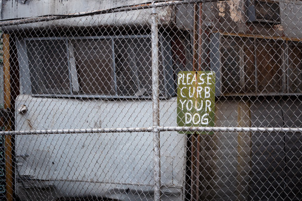 破旧的拖车上写着“请约束你的狗”的牌子图片下载