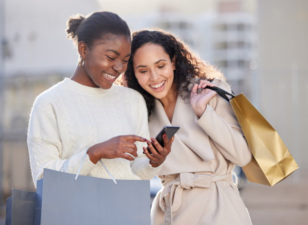 两个朋友在购物时使用智能手机的照片图片下载