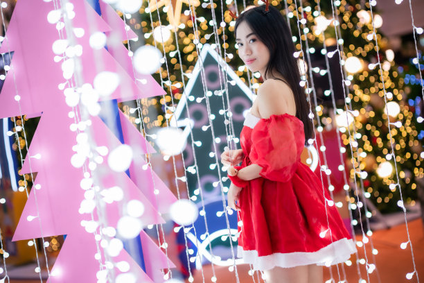 快乐画像年轻的亚洲妇女圣诞老人服装和圣诞祝福画包裹装饰圣诞树上的灯抽象圆形散景背景装饰在圣诞节和新年。图片下载