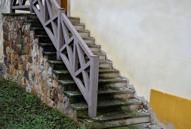 通往建筑物的石阶。这种石头是棕色的，用水泥砂浆粘在一起。楼梯是石板砌成的。栏杆是金属棕色，由坚固的棱柱模仿木结构制成，在楼上图片下载